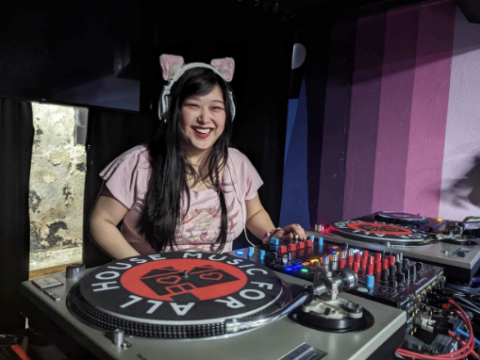 person with cat ear headband by a record player