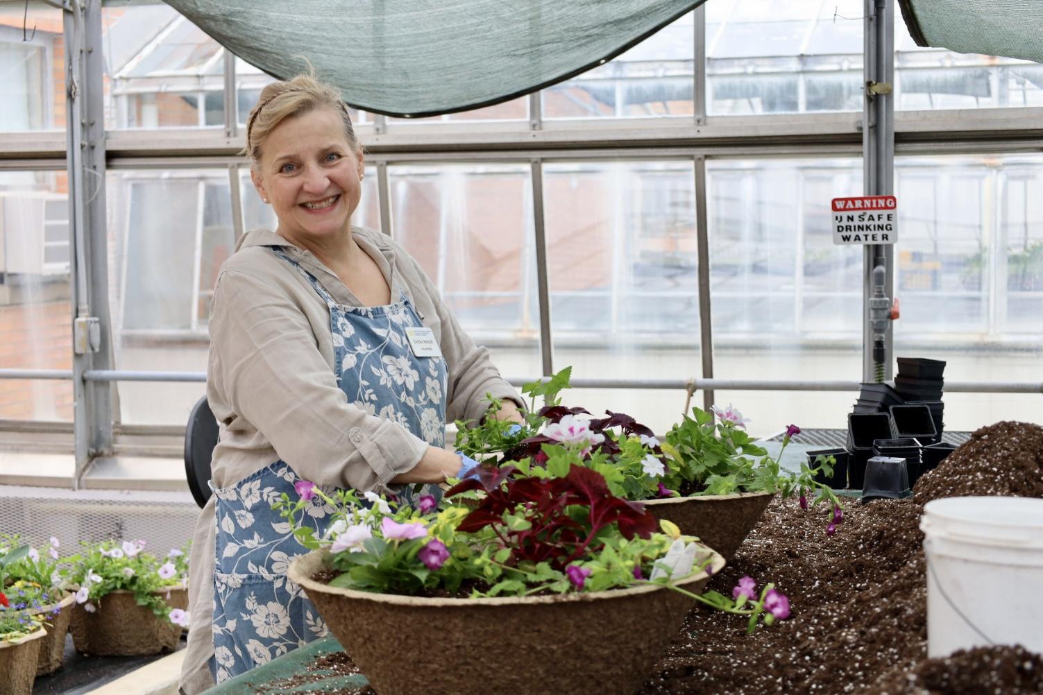 Sarah smiles while planting flowers into a pot