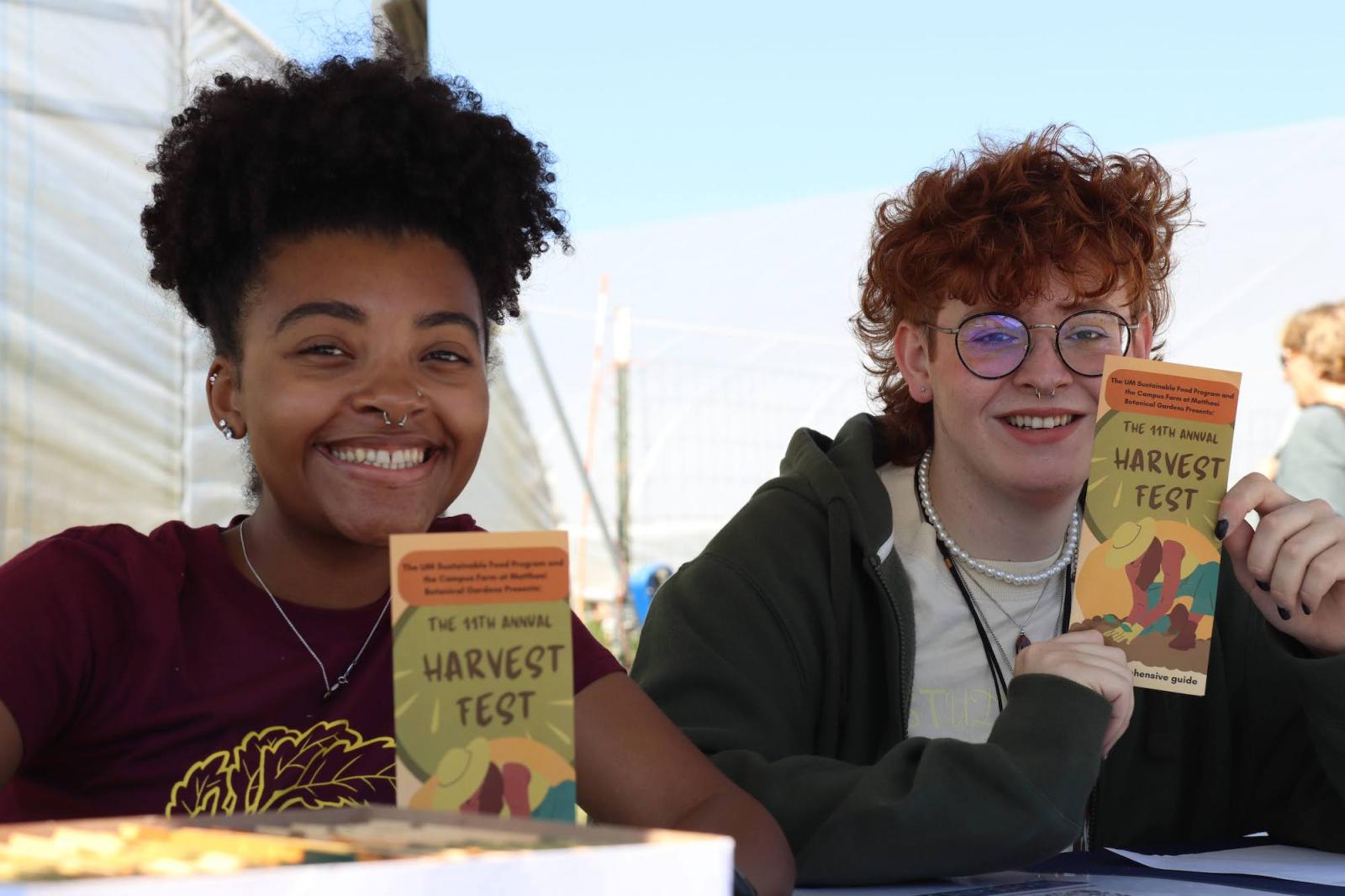 two people hold up Harvest Fest brochures