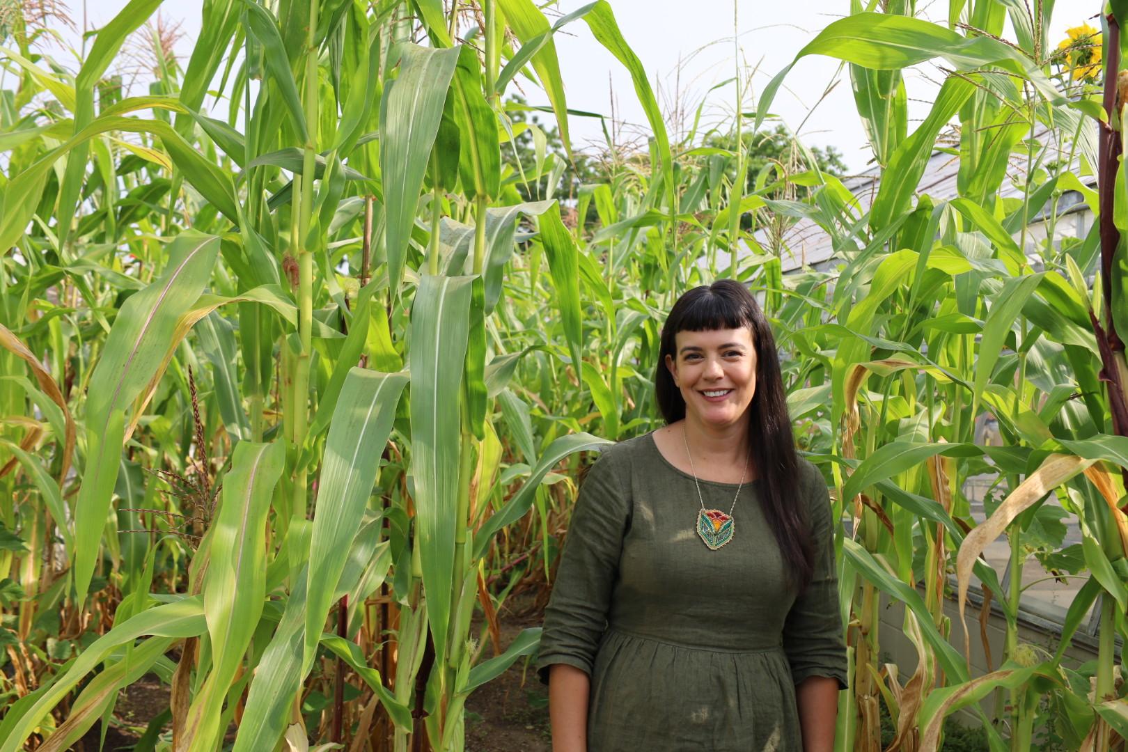 Shiloh Maples stands next to growing corn