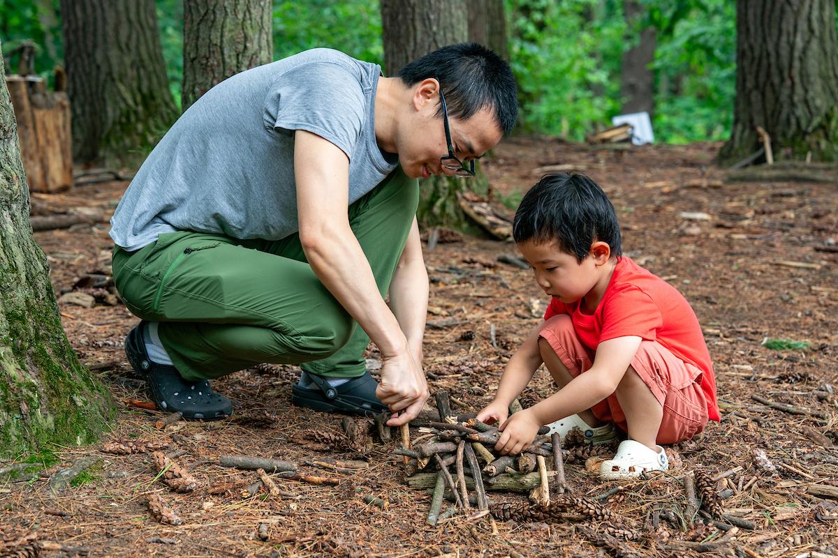 adult and child making a structure out of found sticks