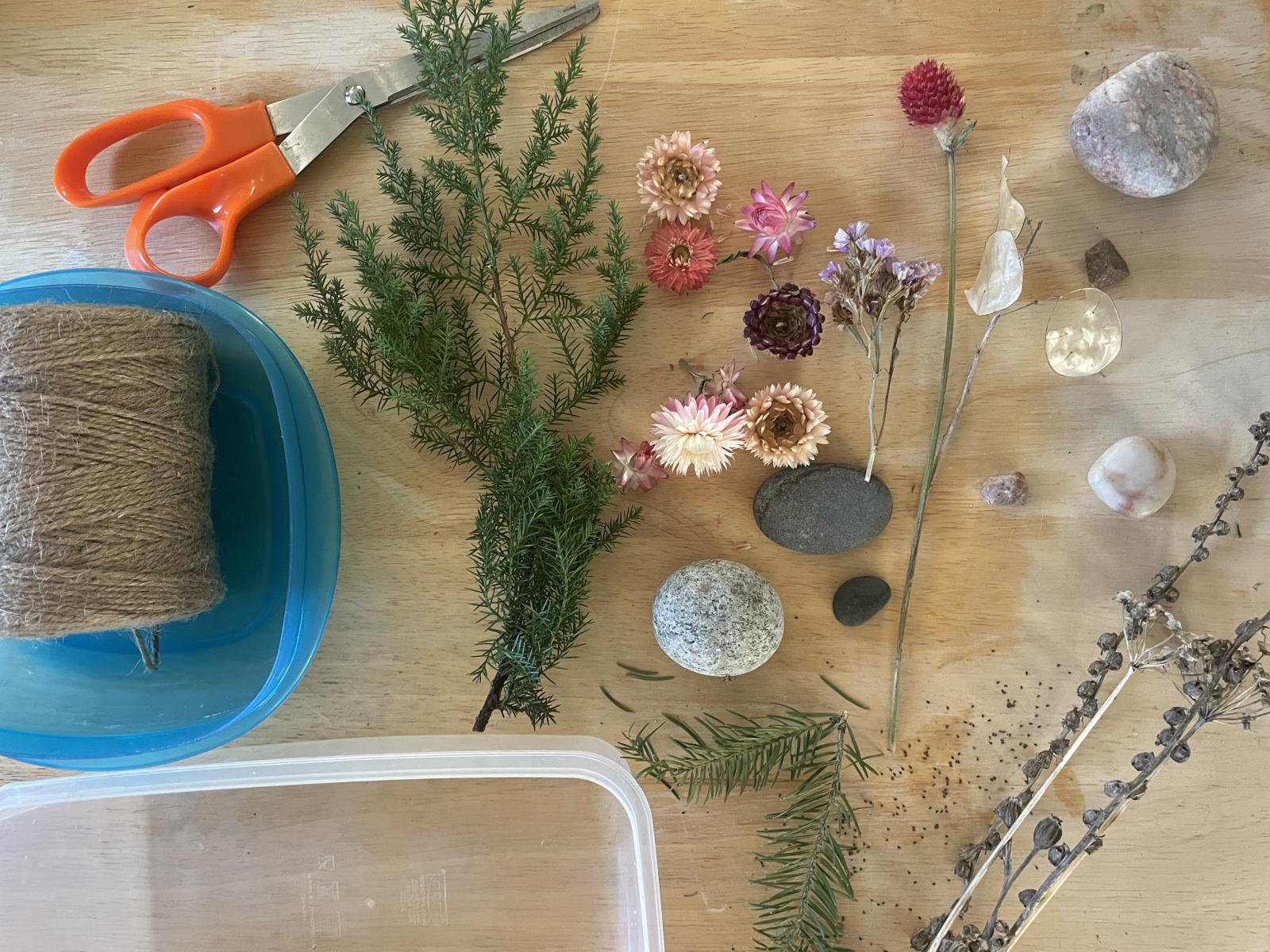 plastic bin with natureal materials next to it along with scissors and twine 