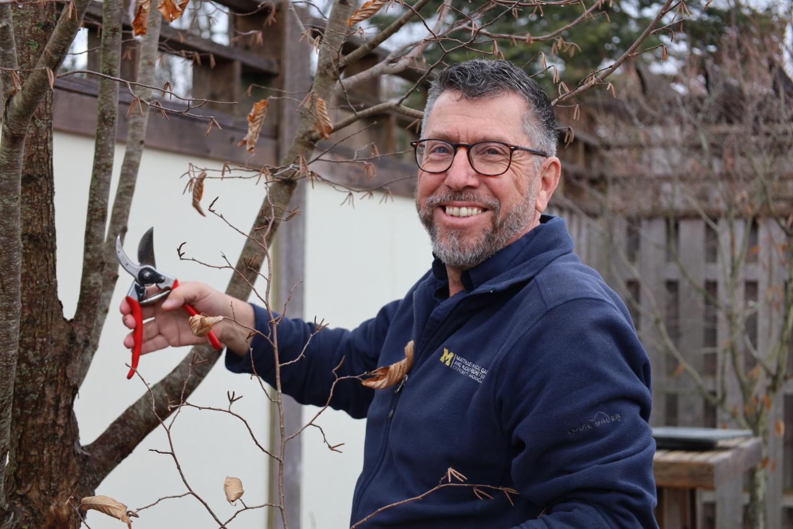 Doug holding trimmers near a branch while smiling