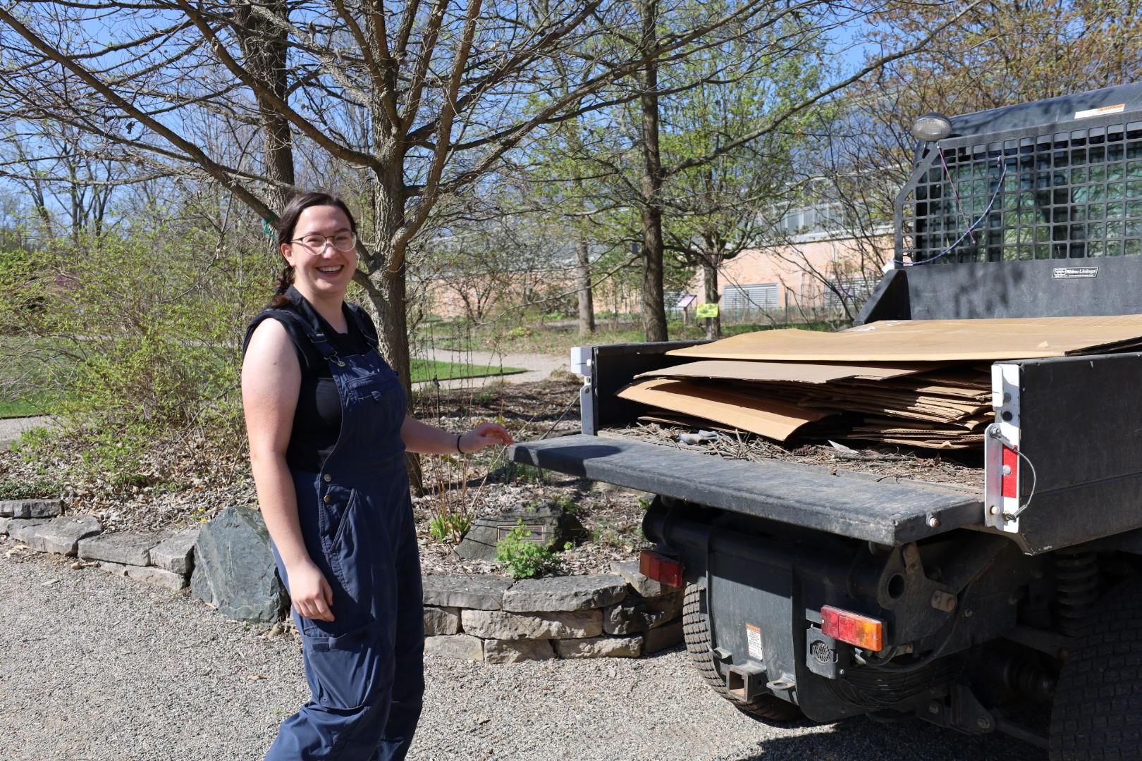 Eve stands next to a small truck filled with sheets of cardboard