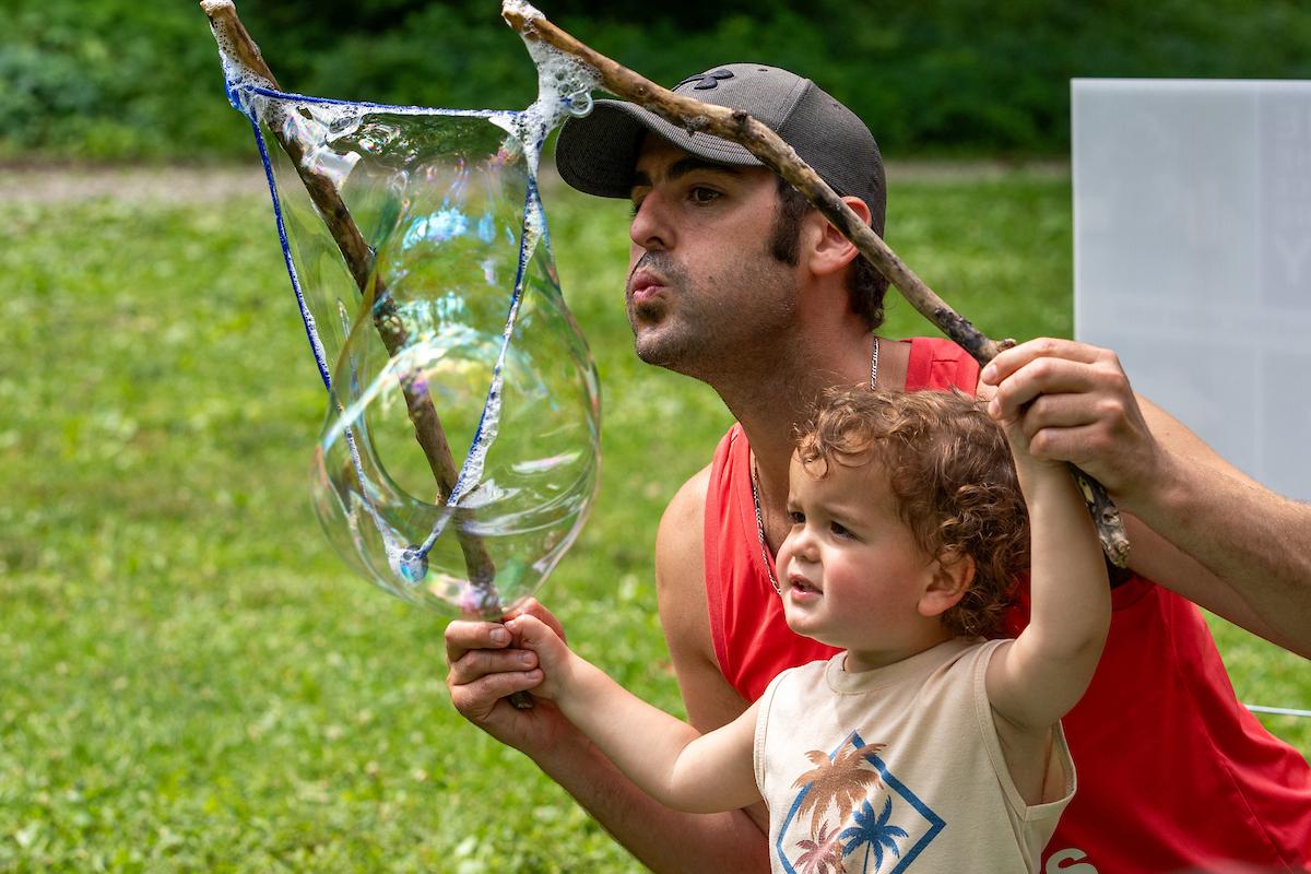 adult and child with sticks and a large bubble