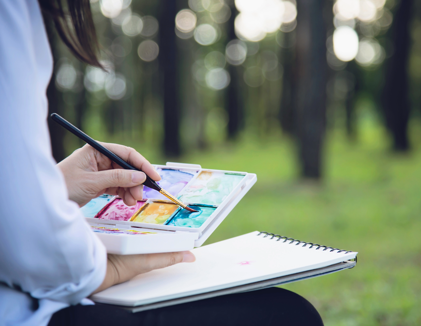 person in nature with watercolor set ready to paint