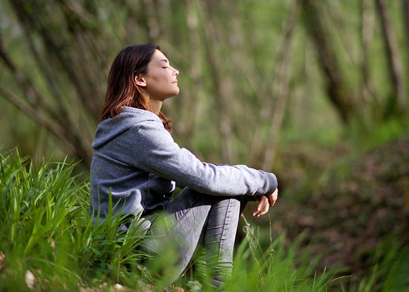 person in nature sitting with eyes closed