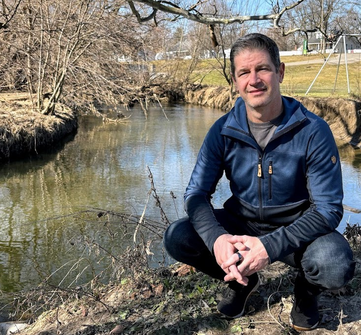 Jacob Napieralski kneeling by river