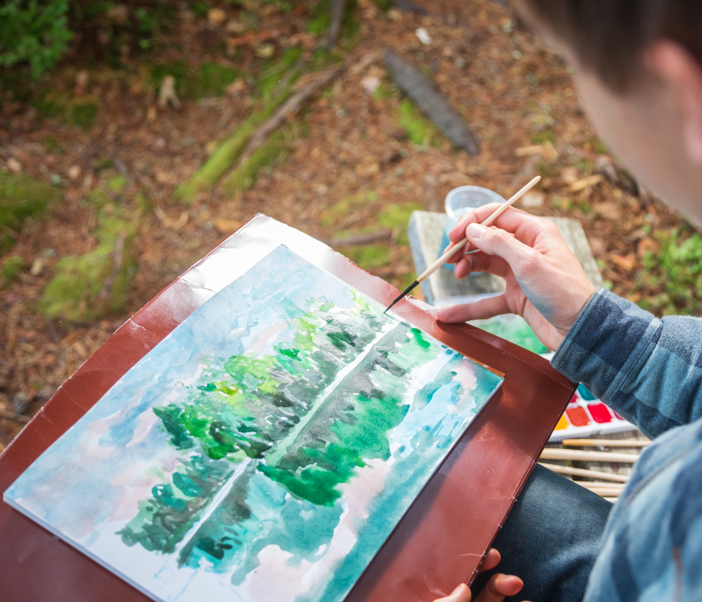 person making watercolor painting in nature