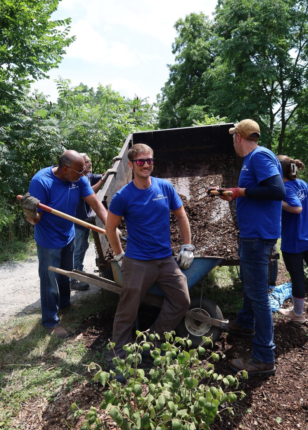 found ford volunteers shovel dirt into a wheelbarrow 