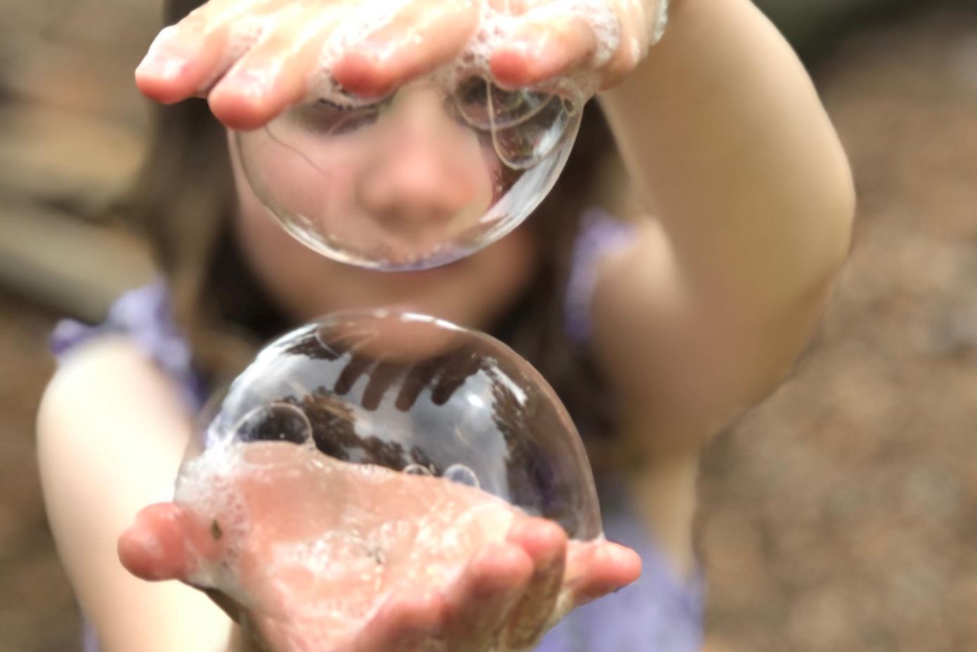 Photo of a child with large soap bubbles on both hands