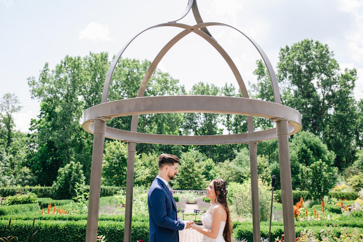 A couple exchanging vows in a wedding ceremony at the herb knot garden