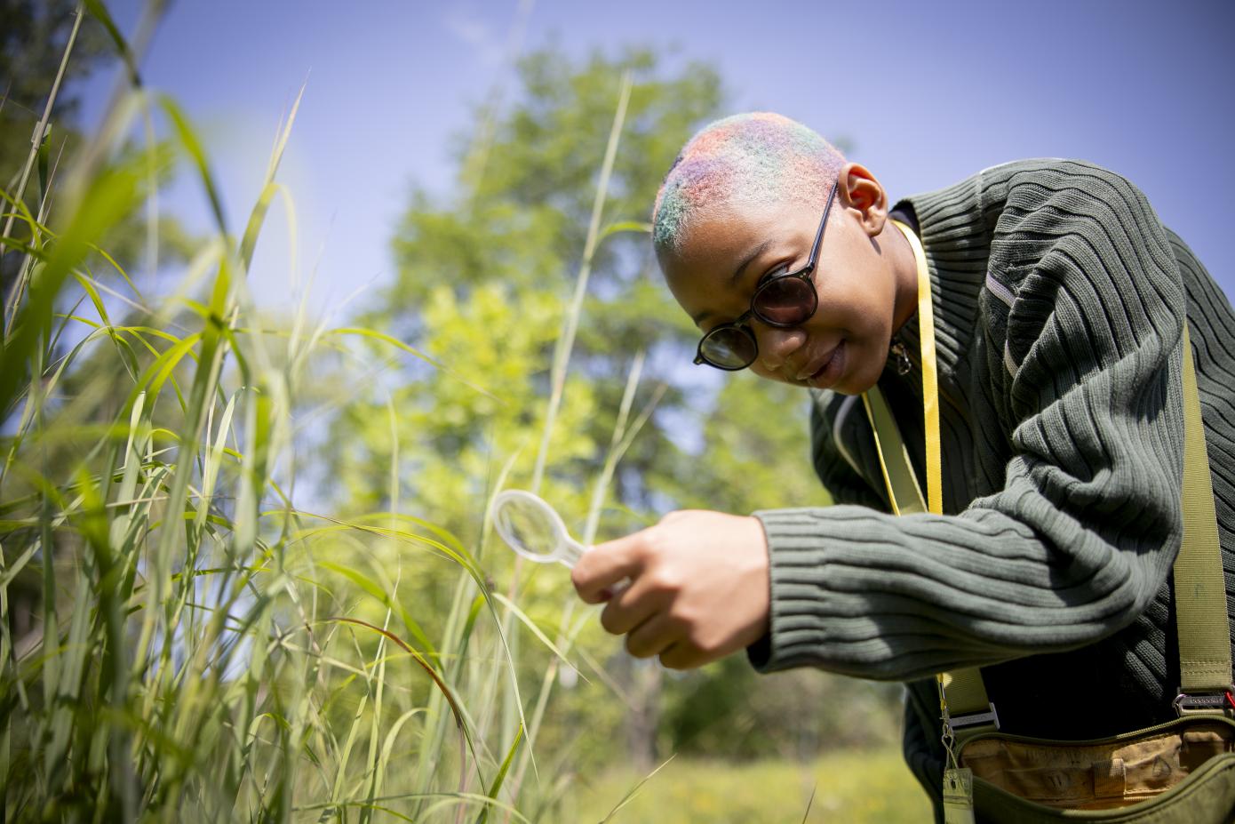 child looks through magnifying glass at plants