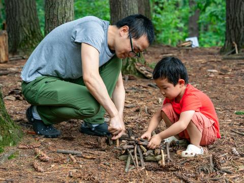 adult and child build with sticks in nature