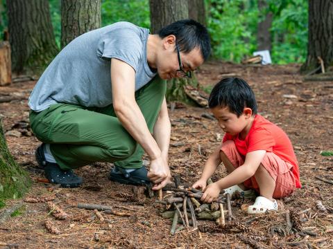 adult and child making a structure out of found sticks