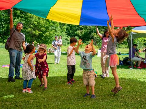 kids under colorful parachute smiling