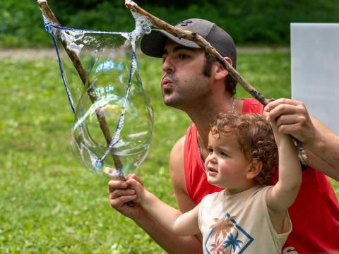 adult and child with sticks and a large bubble