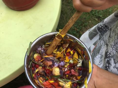 youth hand holding a bowl filled with a play potion of flower petals and water