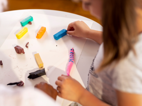 child crafting clay out of colorful clay