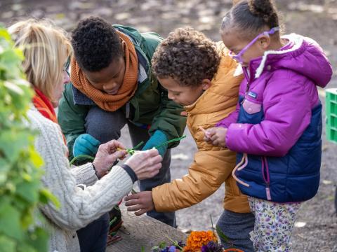 MBGNA's Lee Smith Bravender offers crafting materials to three children dressed in winter coats outdoors.