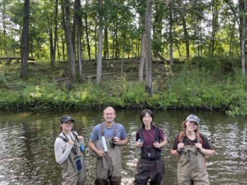 Sydney Lubeck, Cooper Offord, Teresa Li, and Mel Shea wade in Fleming Creek during their fieldwork season in July 2025. 