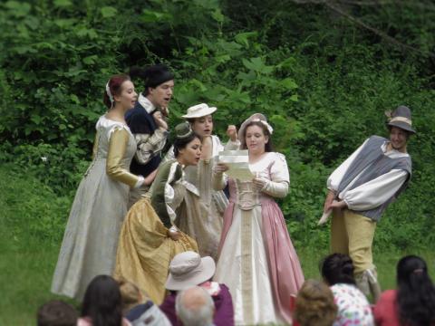 A group of actors lean in to see what another actor is holding