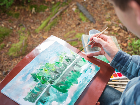 person making watercolor painting in nature