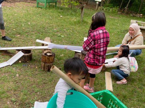 children playing with cardboard and plastic tubes in garden