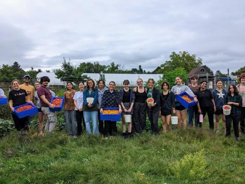 Group of students at the Campus Farm, some holding crates of tomatoes