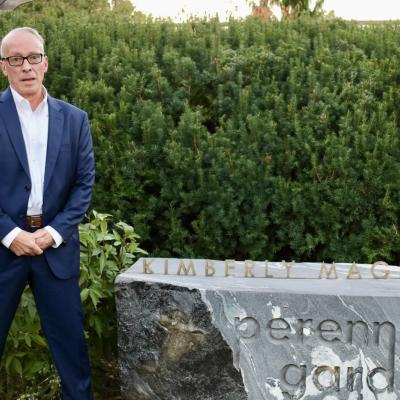 Ted Maged standing in front of stone that says "Kimberly Maged Perennial Garden"