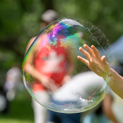 child hand touching a large bubble just before it pops