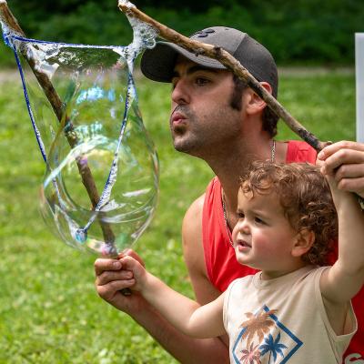 adult and child with sticks and a large bubble