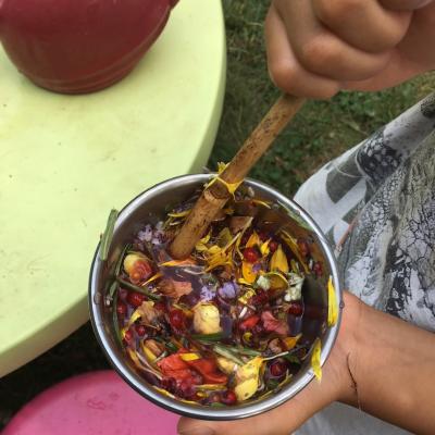 youth hand holding a bowl filled with a play potion of flower petals and water