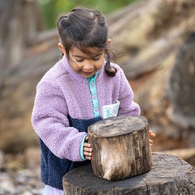 child stacks a log onto another larger log
