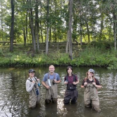 Sydney Lubeck, Cooper Offord, Teresa Li, and Mel Shea wade in Fleming Creek during their fieldwork season in July 2025. 